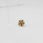 Top-down view of gold ring with square center stone and floral gold petals