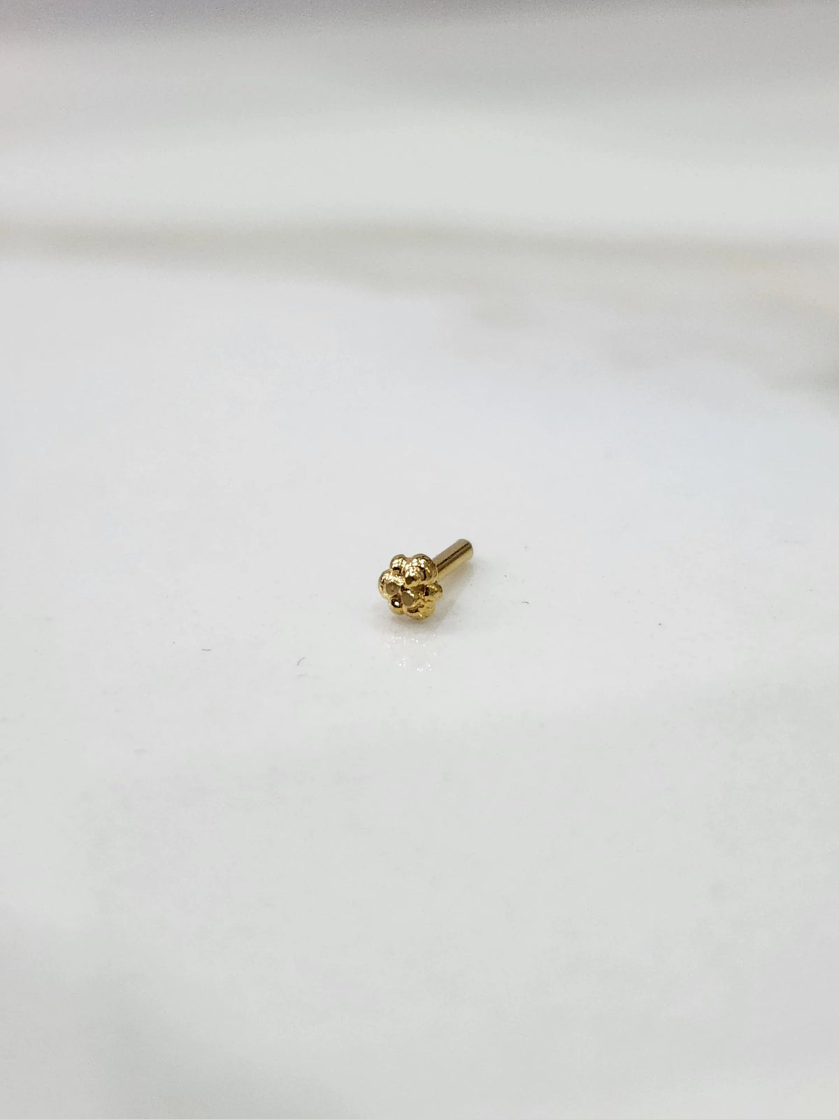 Gold four-leaf clover flower nose pin, angled view showing pin