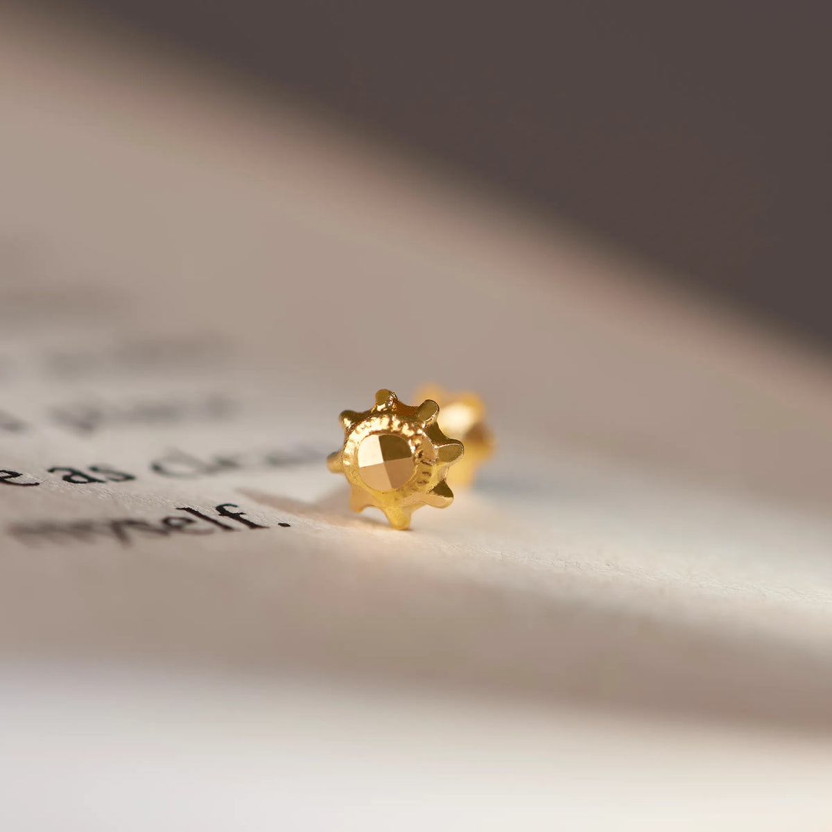 Gold gear-shaped stud earring with faceted center