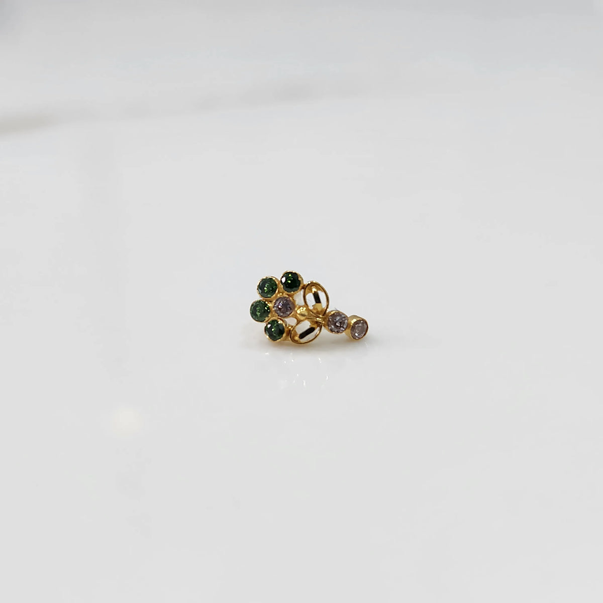 Gold nose pin with green gemstone cluster and clear drop-style stone accent on white background