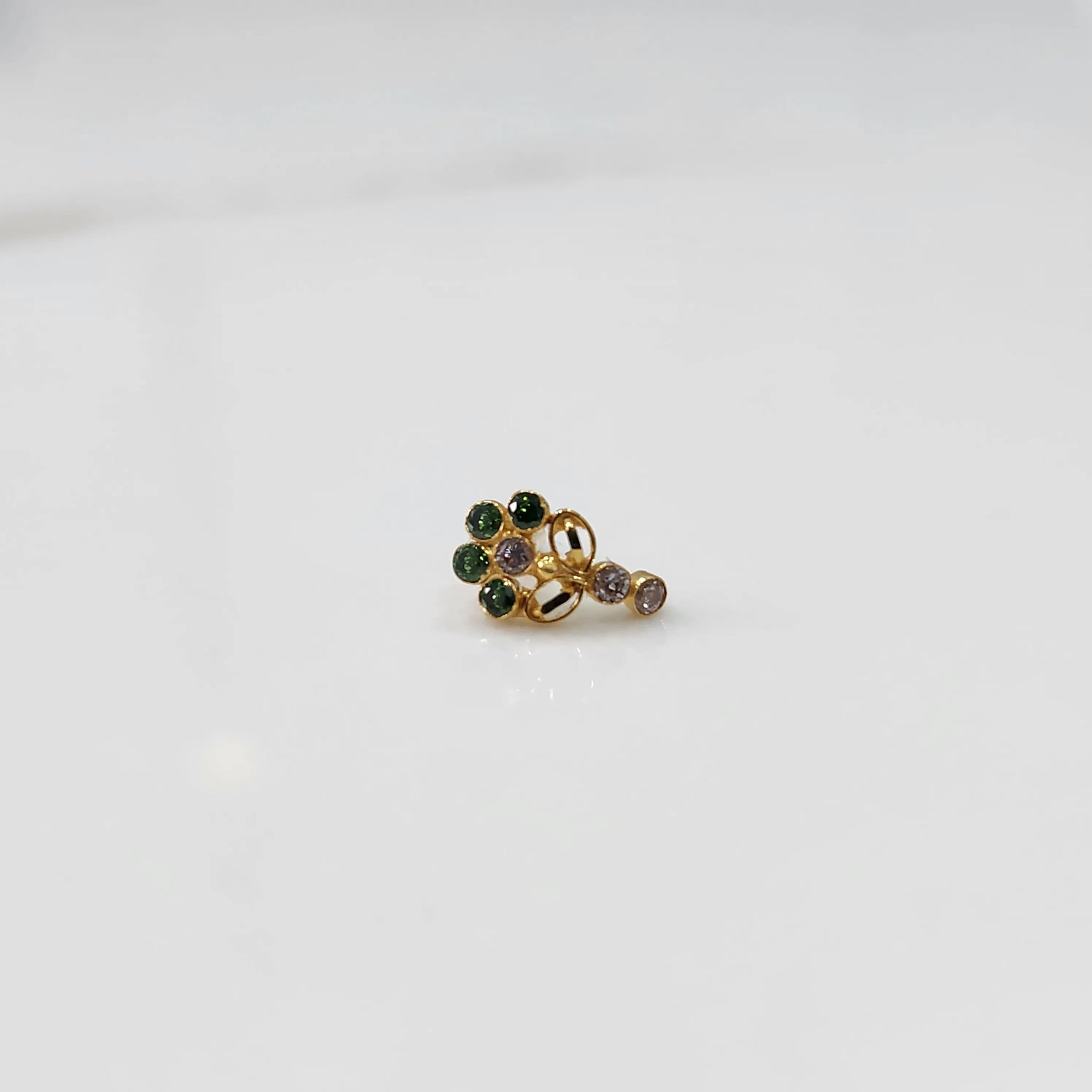 Gold nose pin with green gemstone cluster and clear drop-style stone accent on white background