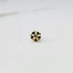 Front view of gold nose pin with green gemstone petals and clear center stone on white background