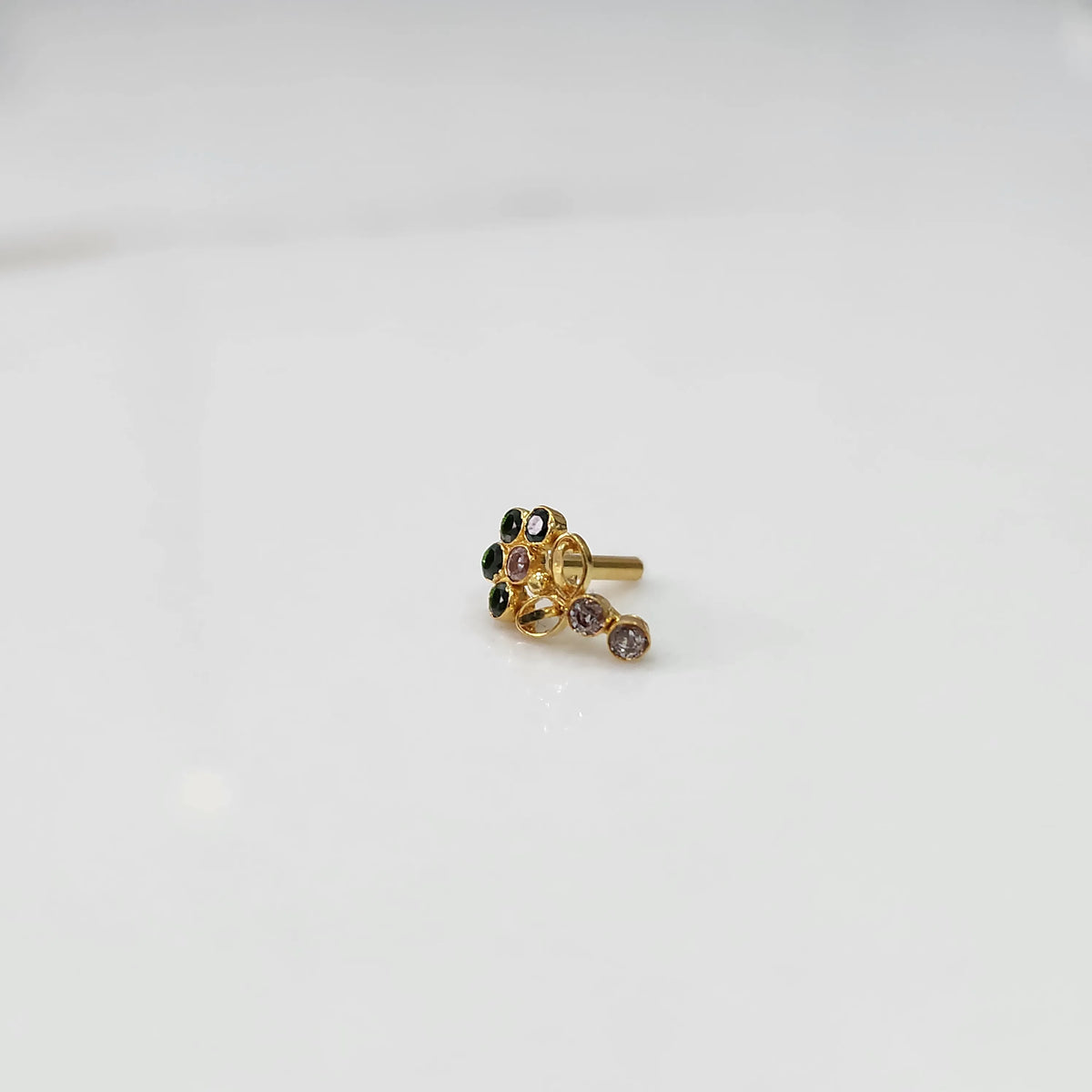 Gold nose pin with green and pink gemstone cluster and lilac drop stone on white background