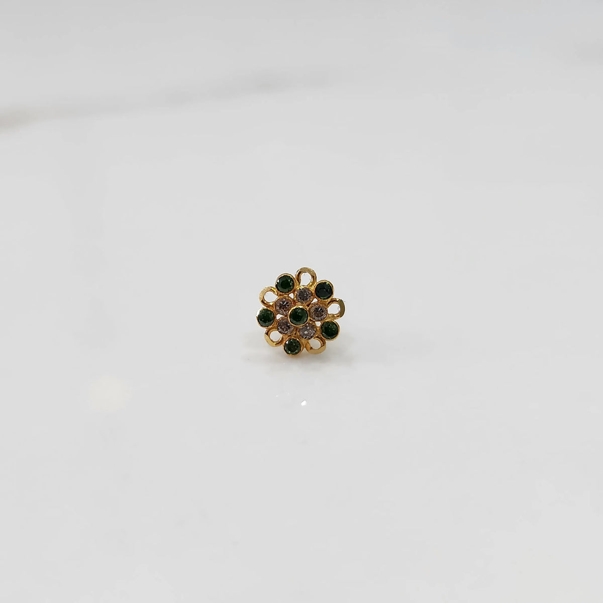 Front view of gold nose pin with green and pink gemstone mandala design on white background