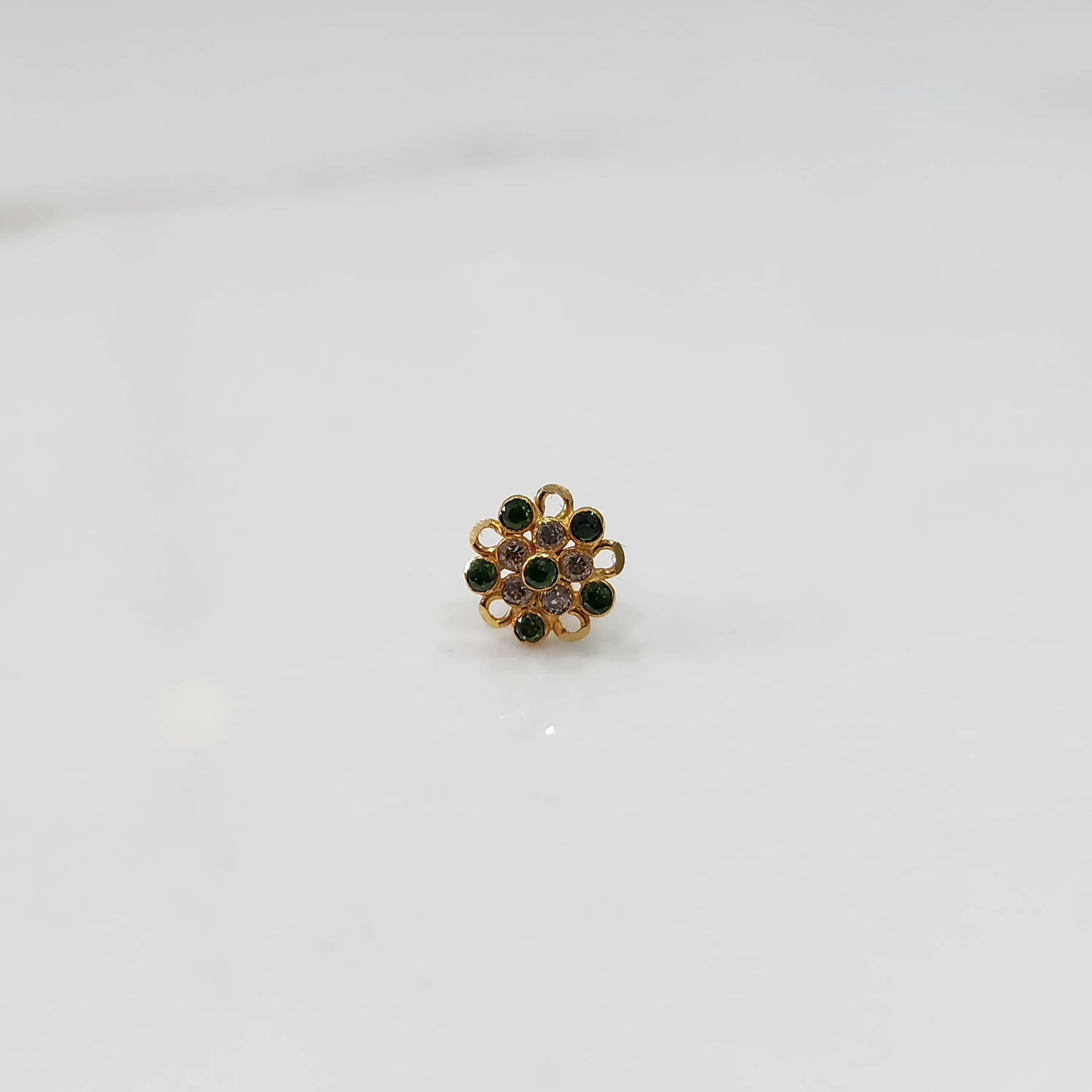 Front view of gold nose pin with green and pink gemstone mandala design on white background