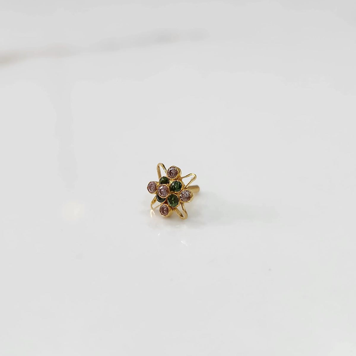 Gold statement ring with green and pink gemstones in floral starburst design