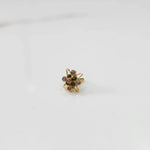 Gold statement ring with green and pink gemstones in floral starburst design