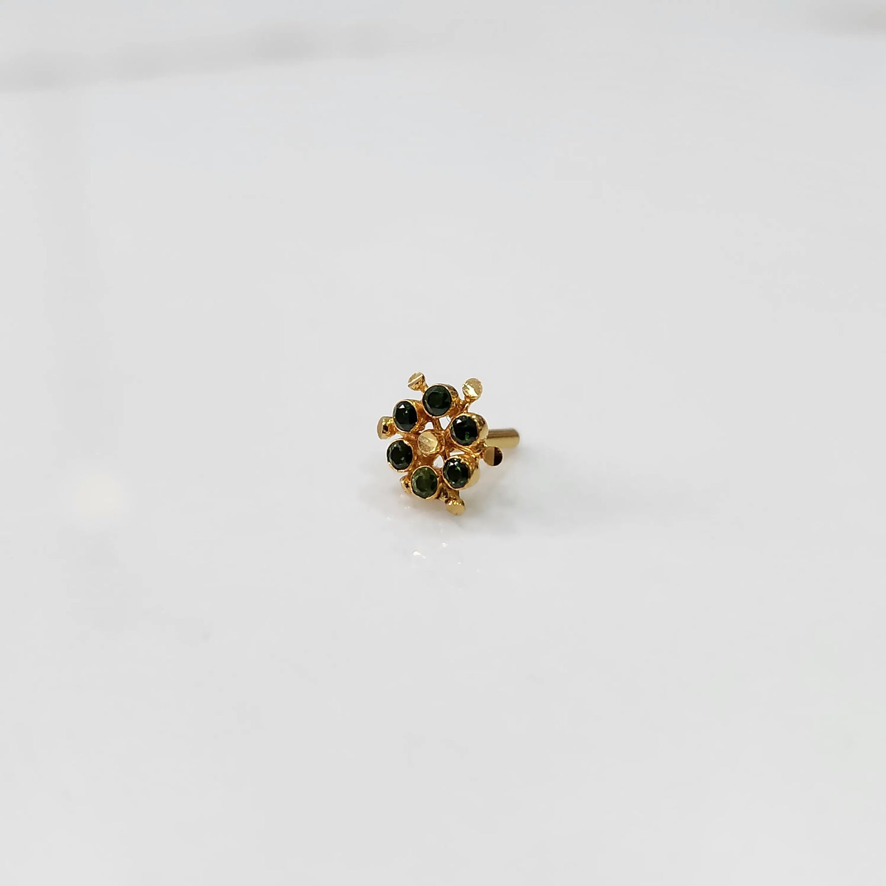 Gold statement ring with green gemstones in scattered dotted cluster design