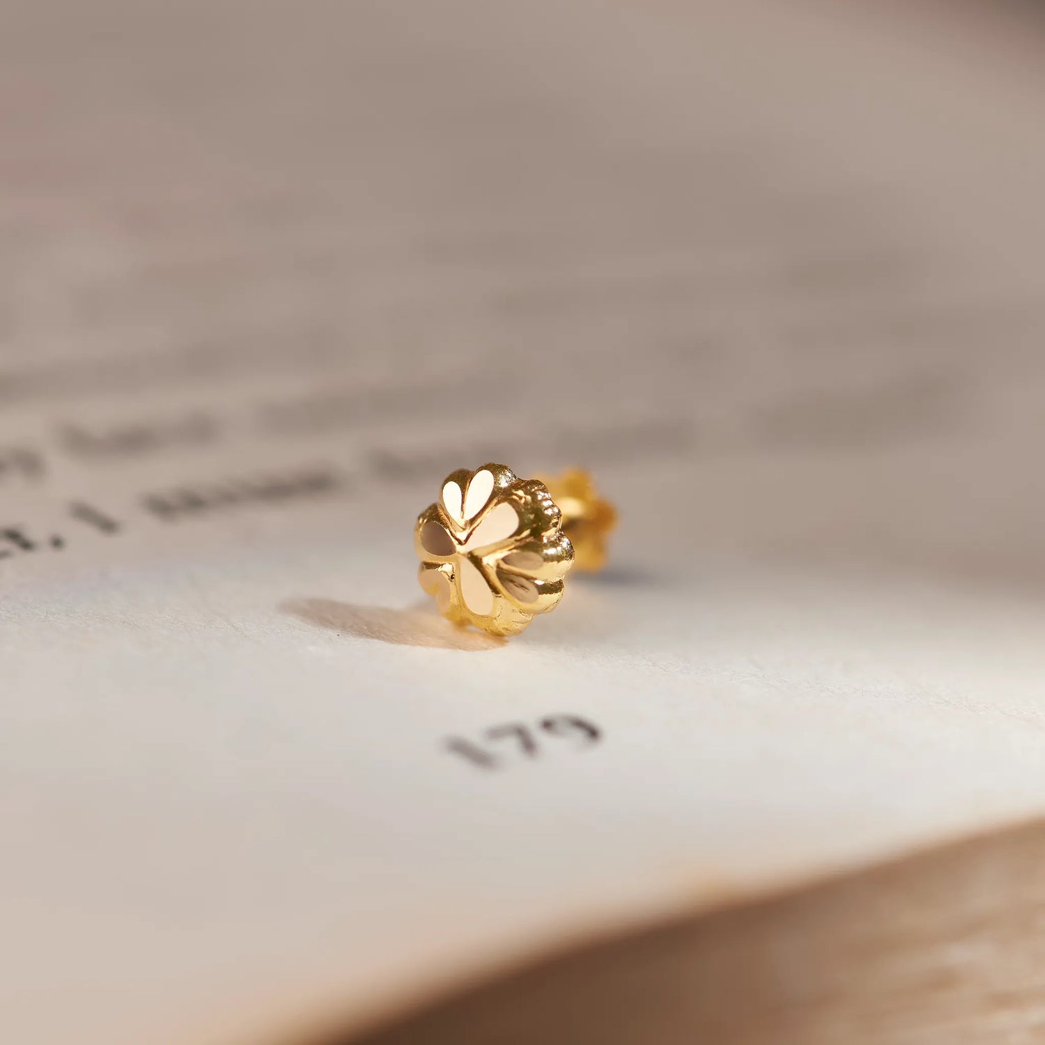 Gold clover-shaped stud earring with heart-petal design, close-up