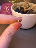 Small gold heart-shaped nose pin stud held on fingertip