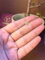 Small heart-shaped gold nose pin held in hand, showing Yuvora jewelry brand packaging in the background