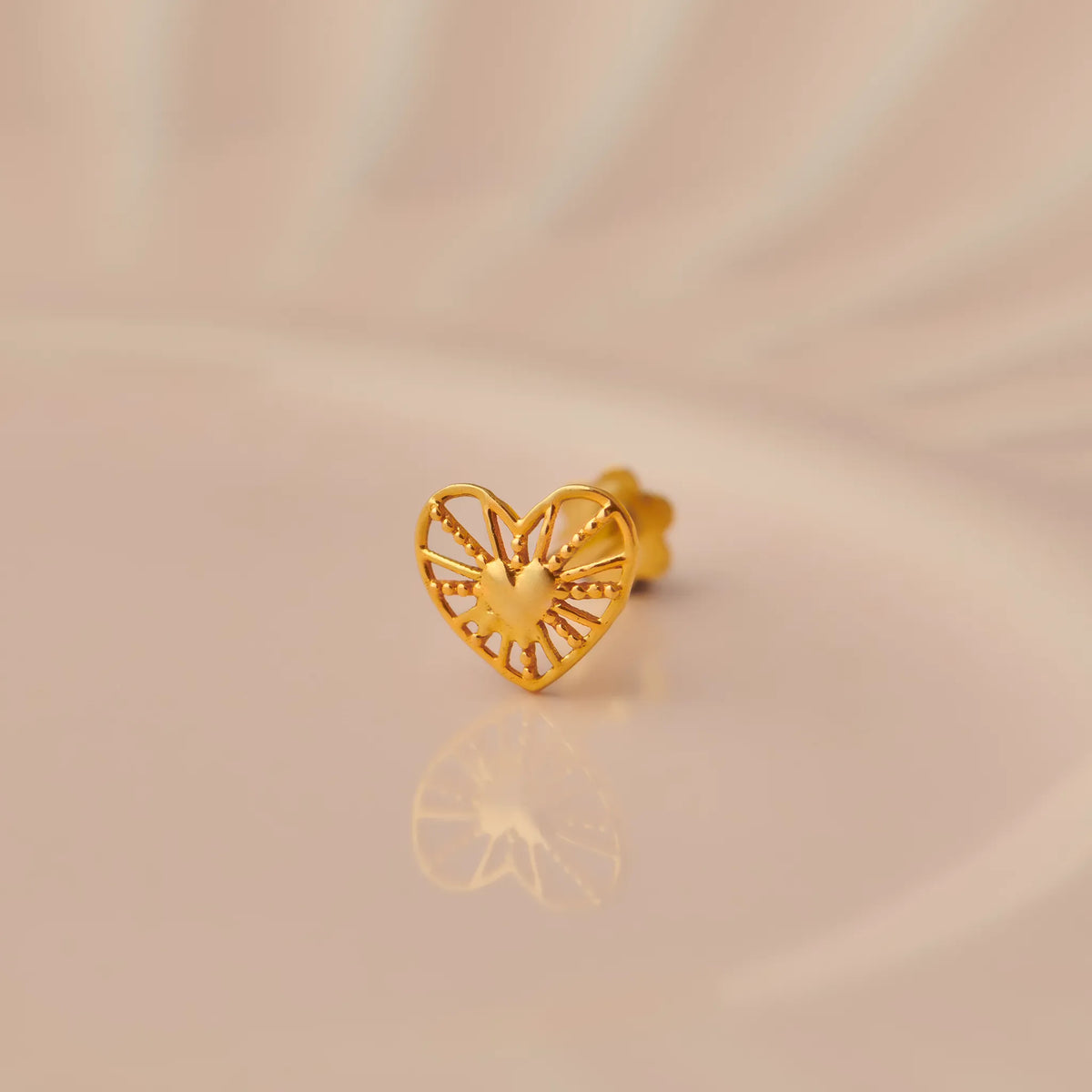 Gold heart-shaped stud earring with radial cutout design