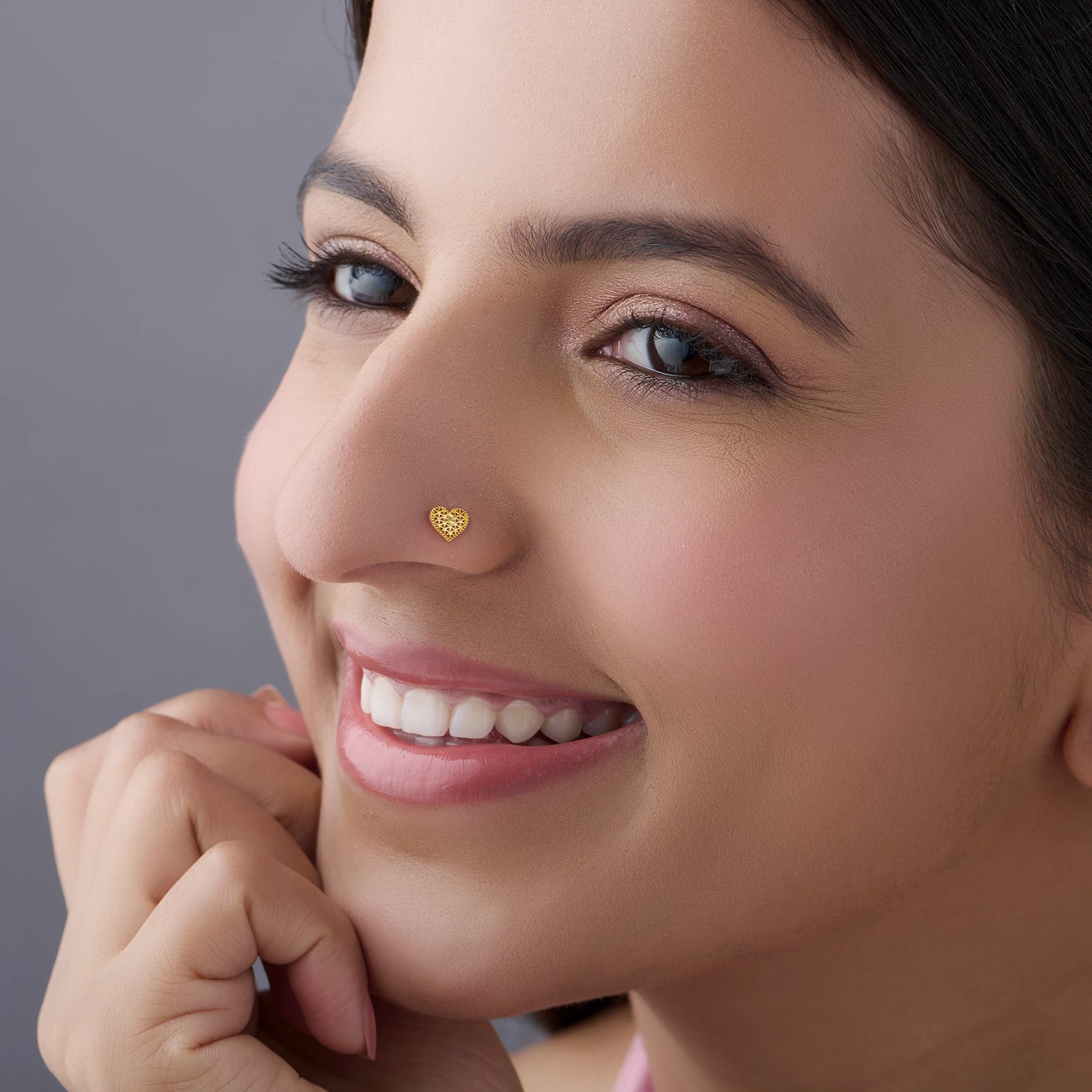Smiling woman wearing gold heart-shaped nose pin