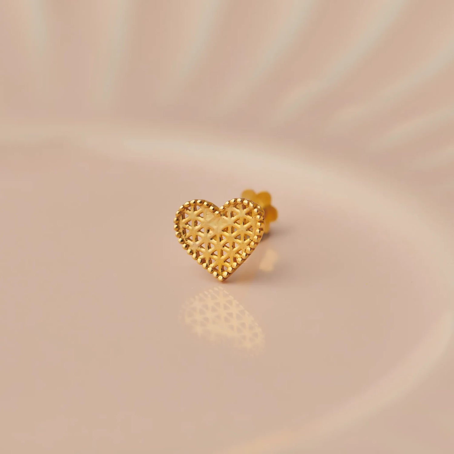 Gold heart-shaped stud earring with textured geometric pattern