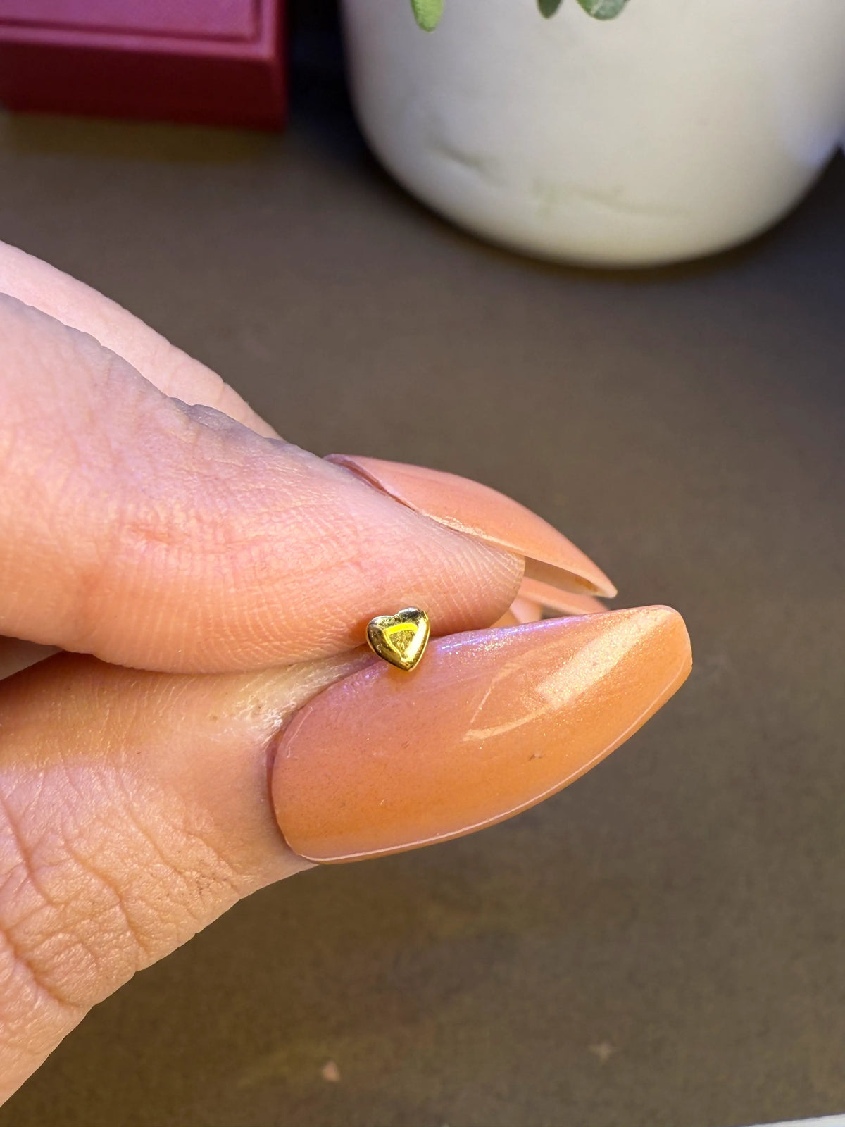 Hand holding a tiny 18K nose pin gold to display its small lightweight size