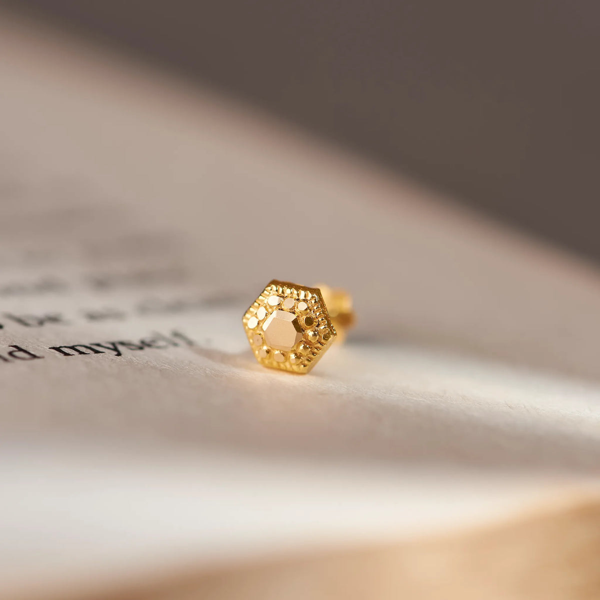 Gold honeycomb-shaped earring with beaded edge