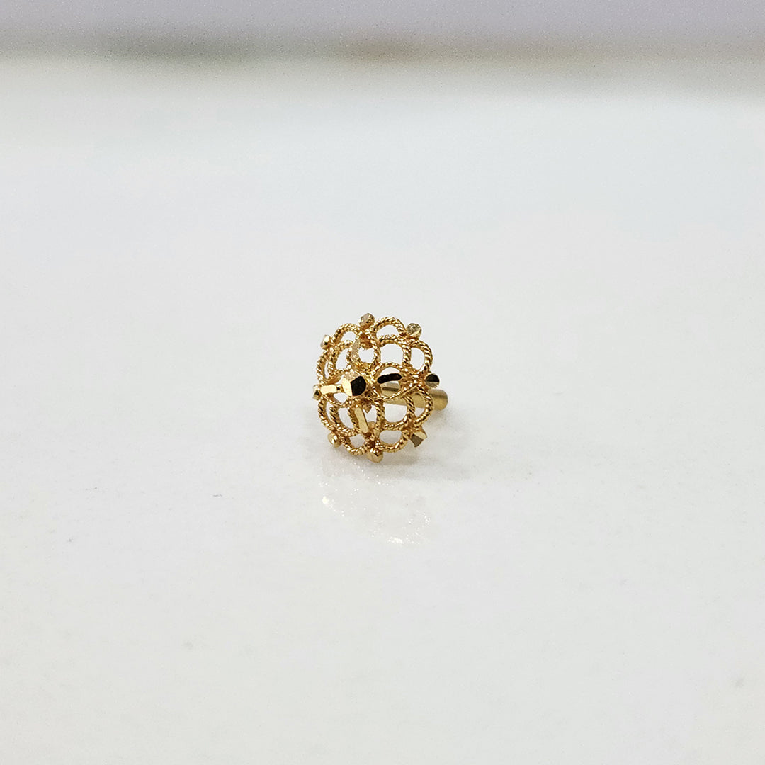 Round gold nose pin with an intricate lace-like filigree design on a white surface