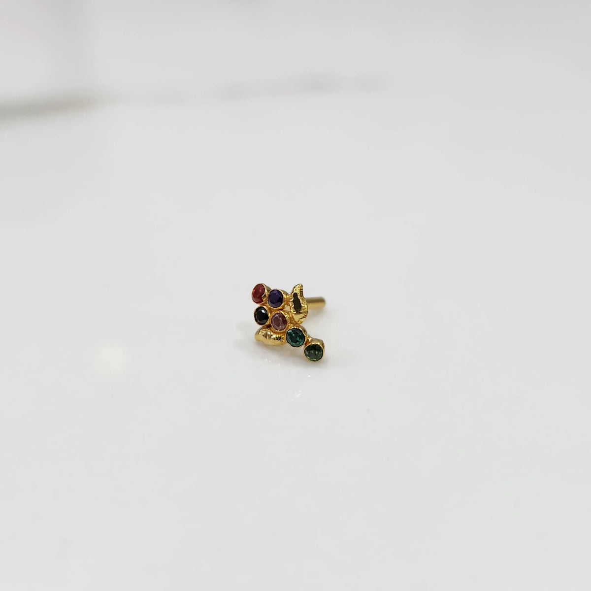Side view of gold ring featuring multicolor gemstone cluster with leaf and drop accent