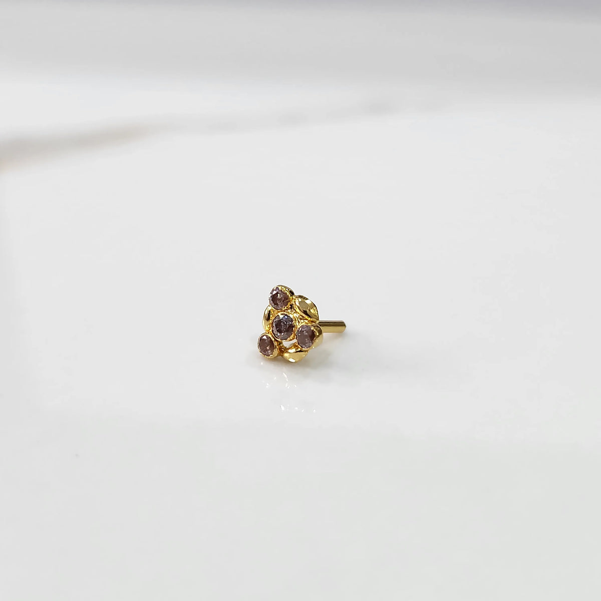 Antique-style gold ring with pink-toned stones in leaf-petal pattern, angled view