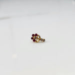 Front view of gold nose pin with magenta gemstone cluster and clear drop-style stone accent on white background