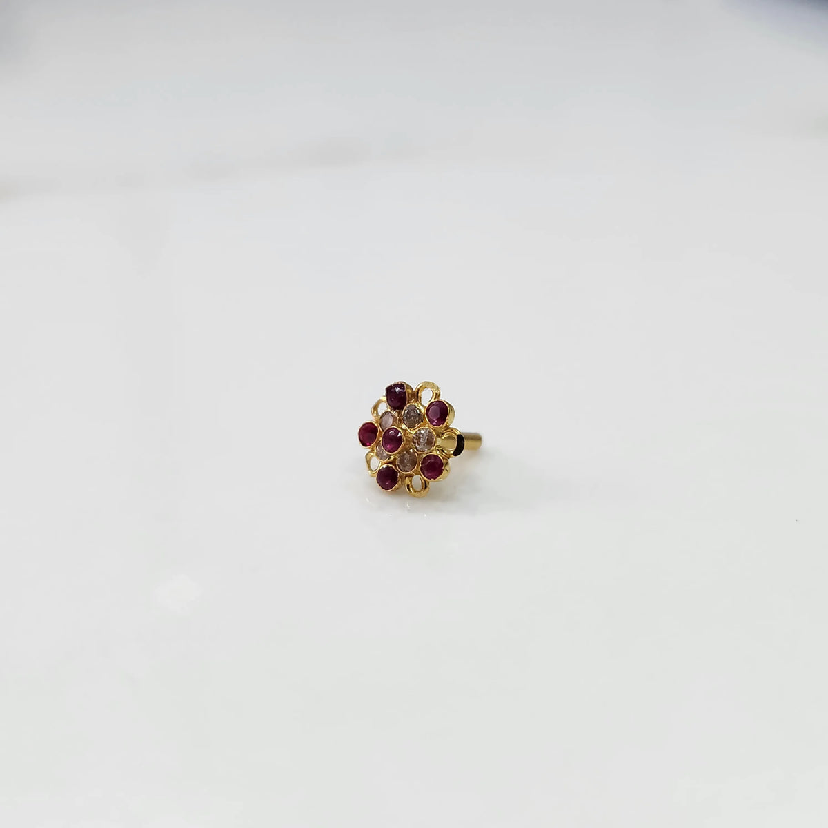Gold nose pin with magenta gemstone mandala design on white background 
