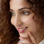 Woman wearing round mandala-style gold nose pin, close-up