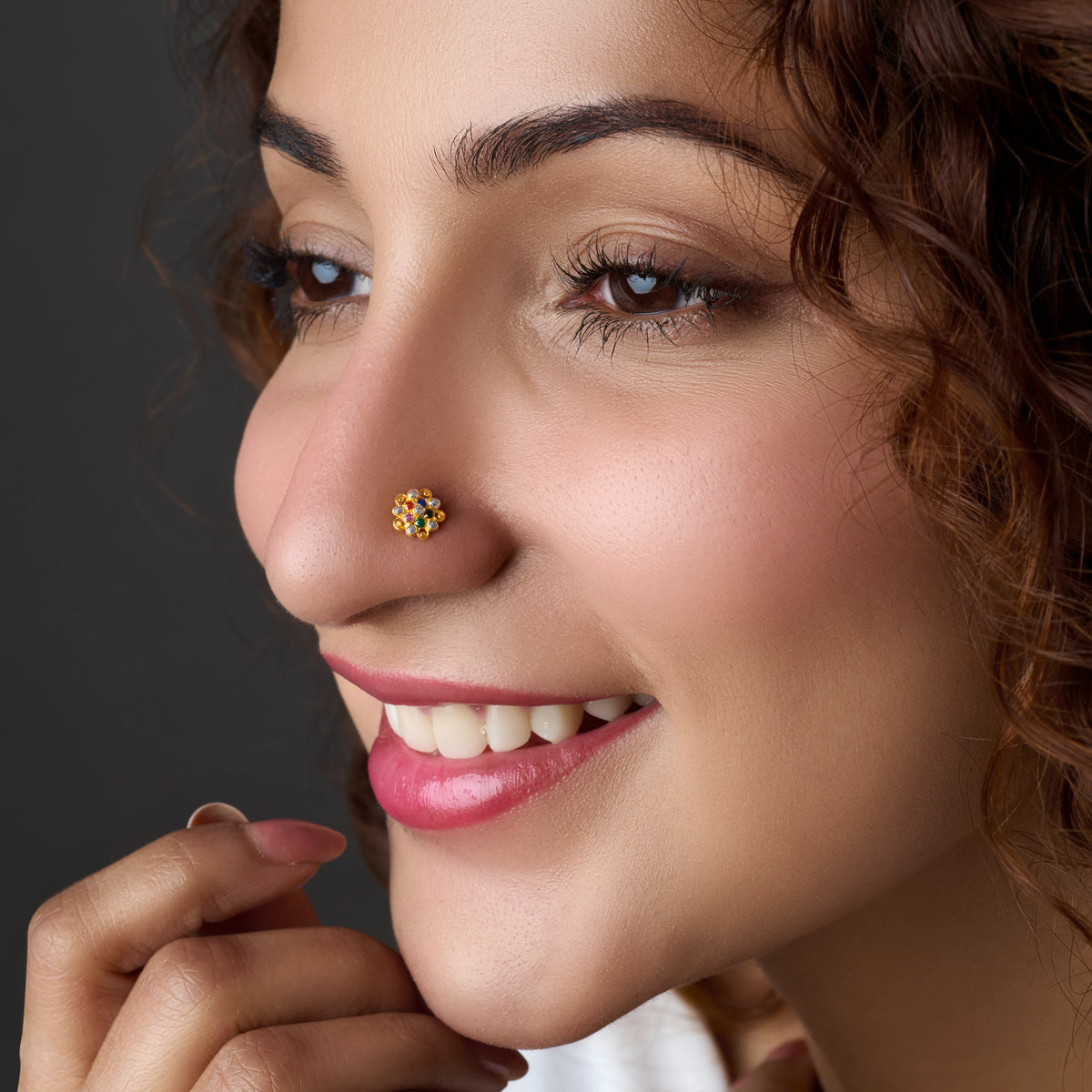 Woman wearing a floral gold nose pin with multicolor stones