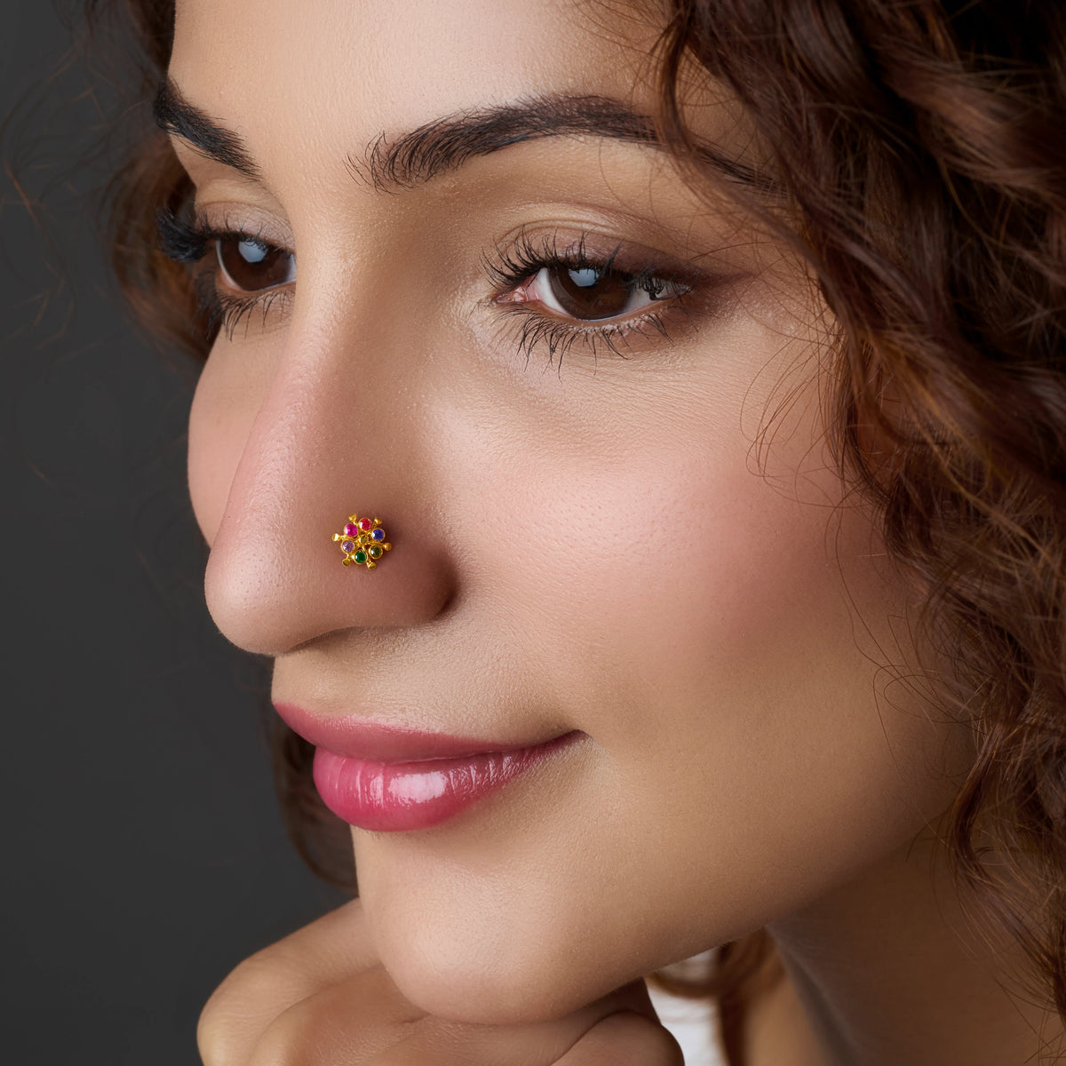 Close-up of flower-shaped gold nose stud with colorful gems