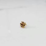 Angled view of gold nose pin with multicolor gemstone flower design on white background