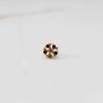 Front view of gold nose pin with multicolor gemstone petals and clear center stone on white background