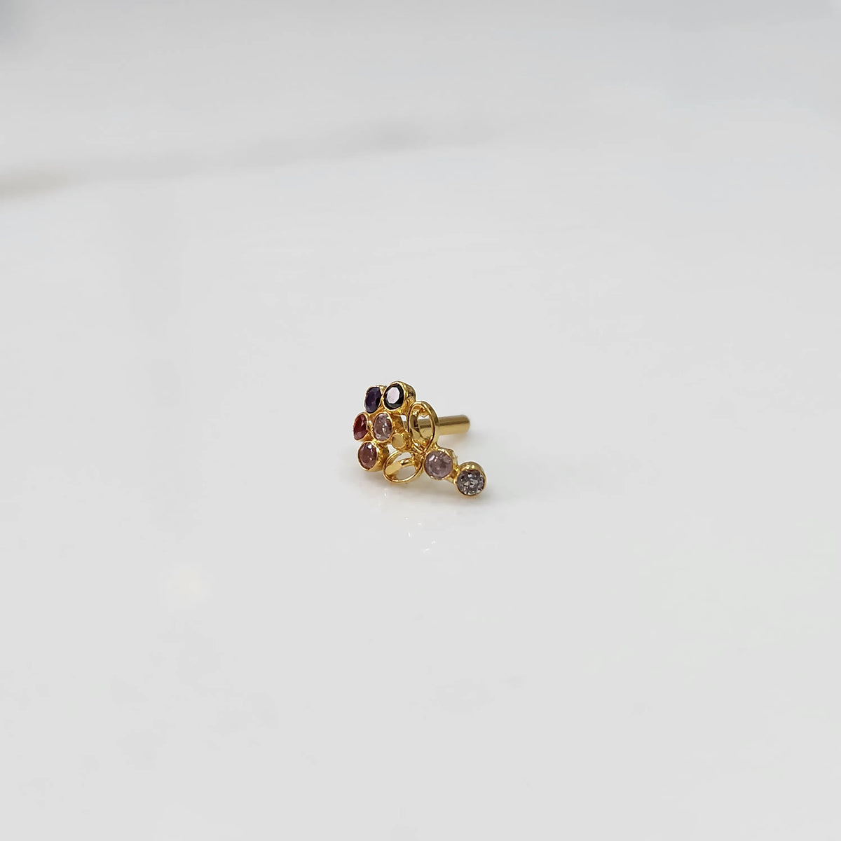 Gold nose pin with multicolor gemstone cluster and drop-style stone accent on white background