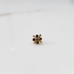 Front view of gold nose pin with multicolor gemstone flower design on white background