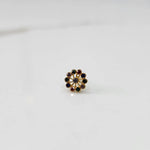 Front view of large gold nose pin with multicolor gemstone flower ring design on white background