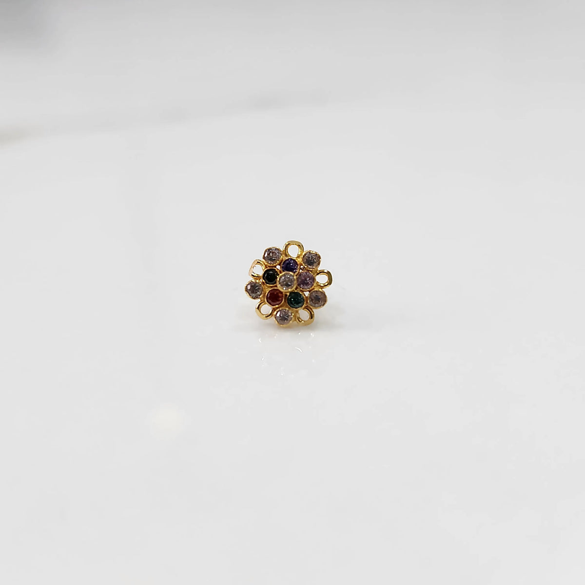 Front view of gold nose pin with multicolor gemstone mandala design on white background