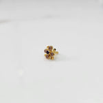 Side angle view of gold nose pin with multicolor gemstone flower design on white background