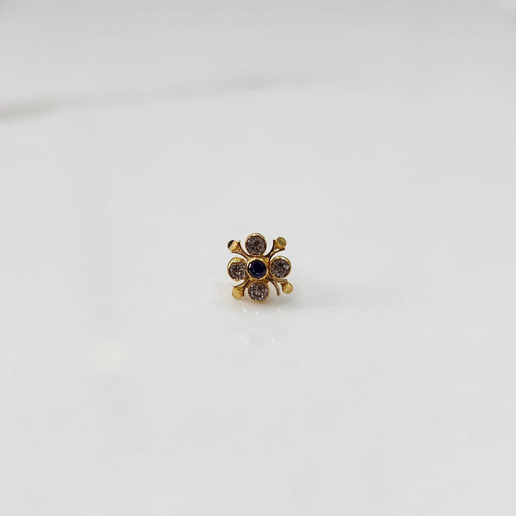 Gold nose pin with multicolor gemstone flower design, cropped product shot on white background