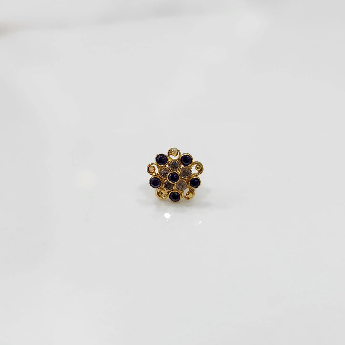Gold flower ring with purple and clear gemstones in halo setting