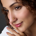 Woman wearing a round gold nose pin with multicolor stones