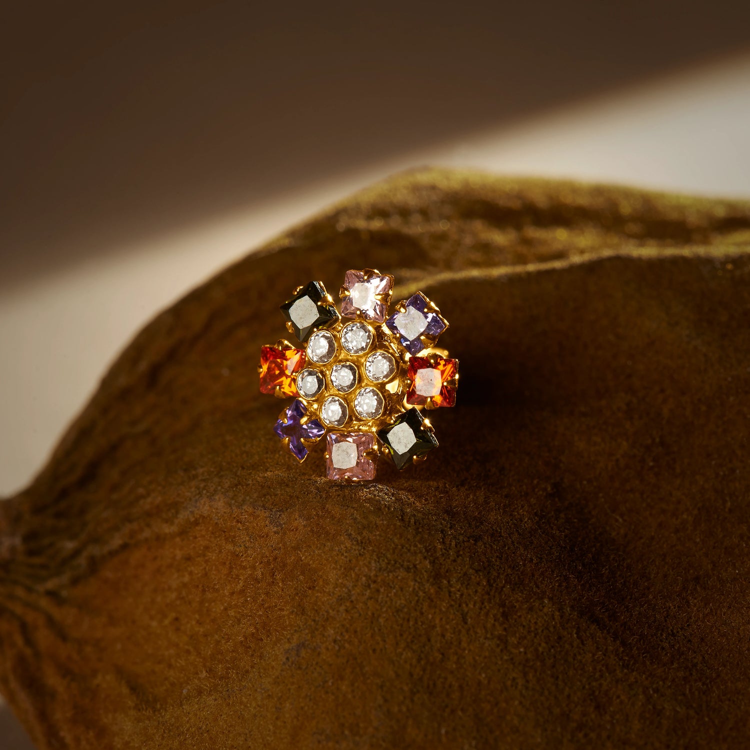 Gold nose pin design with multicolor floral stones on textured surface