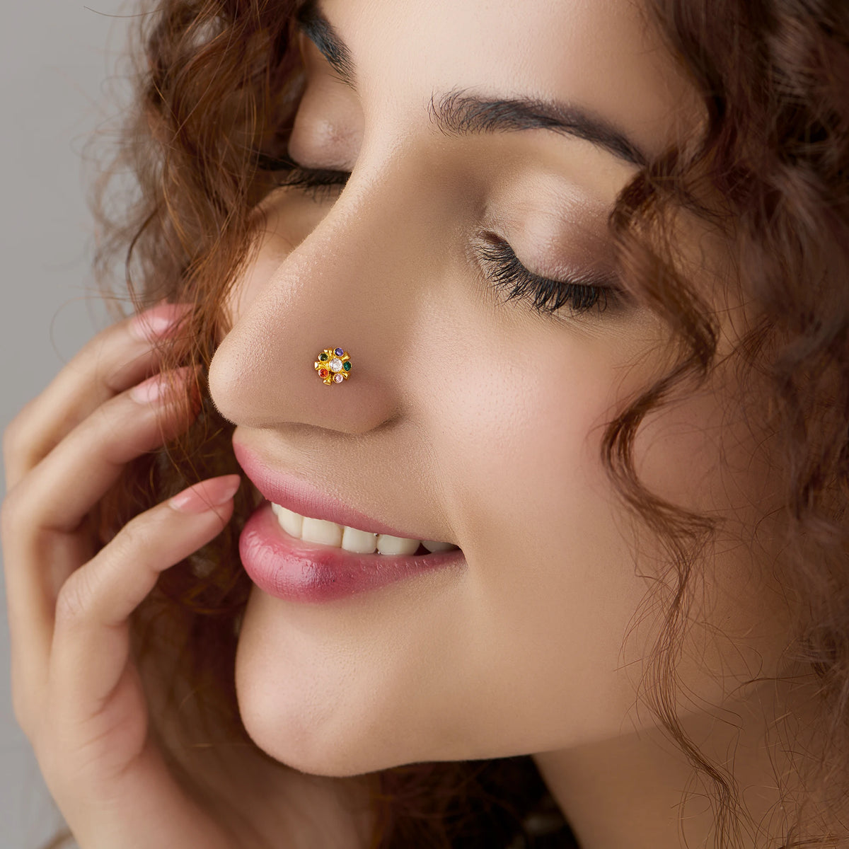 Woman wearing gold floral nose pin with multicolor stones