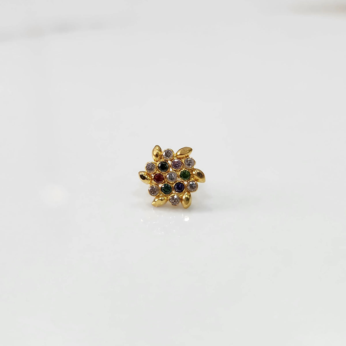 Front view of gold statement ring with multicolor gemstones in leaf-patterned cluster design
