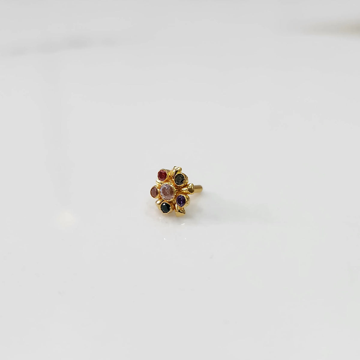 Side view of gold statement ring with multicolor gemstones and leaf-patterned setting