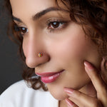 Woman wearing a gold nose pin with multicolor stones