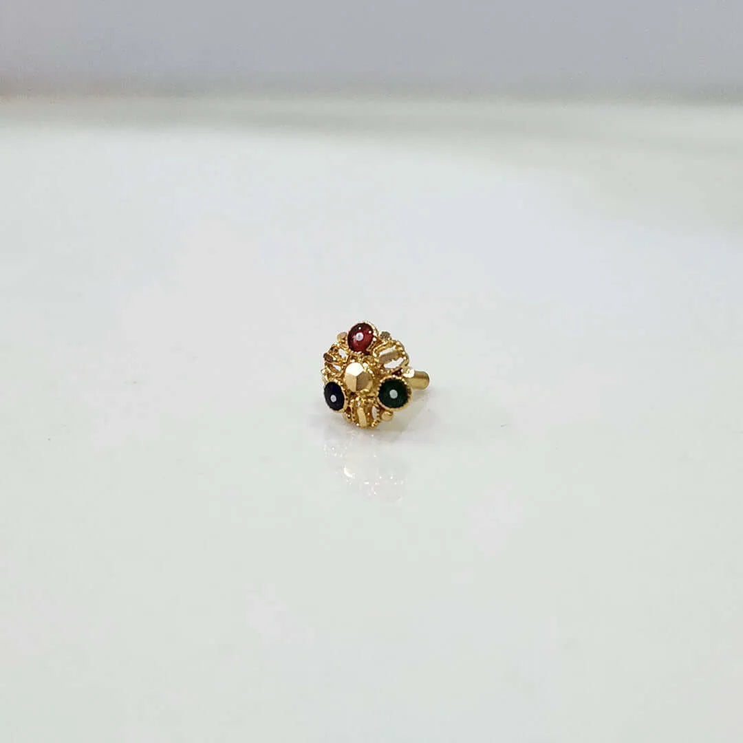 Gold nose pin with red and green gemstones in a floral filigree design