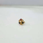 Gold nose pin with red and green gemstones in a floral filigree design