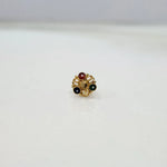 Front view of a gold nose pin with red, green, black, and gold gemstones in a floral cluster design