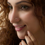 Gold star diamond nose stud worn by a smiling woman, close-up beauty shot