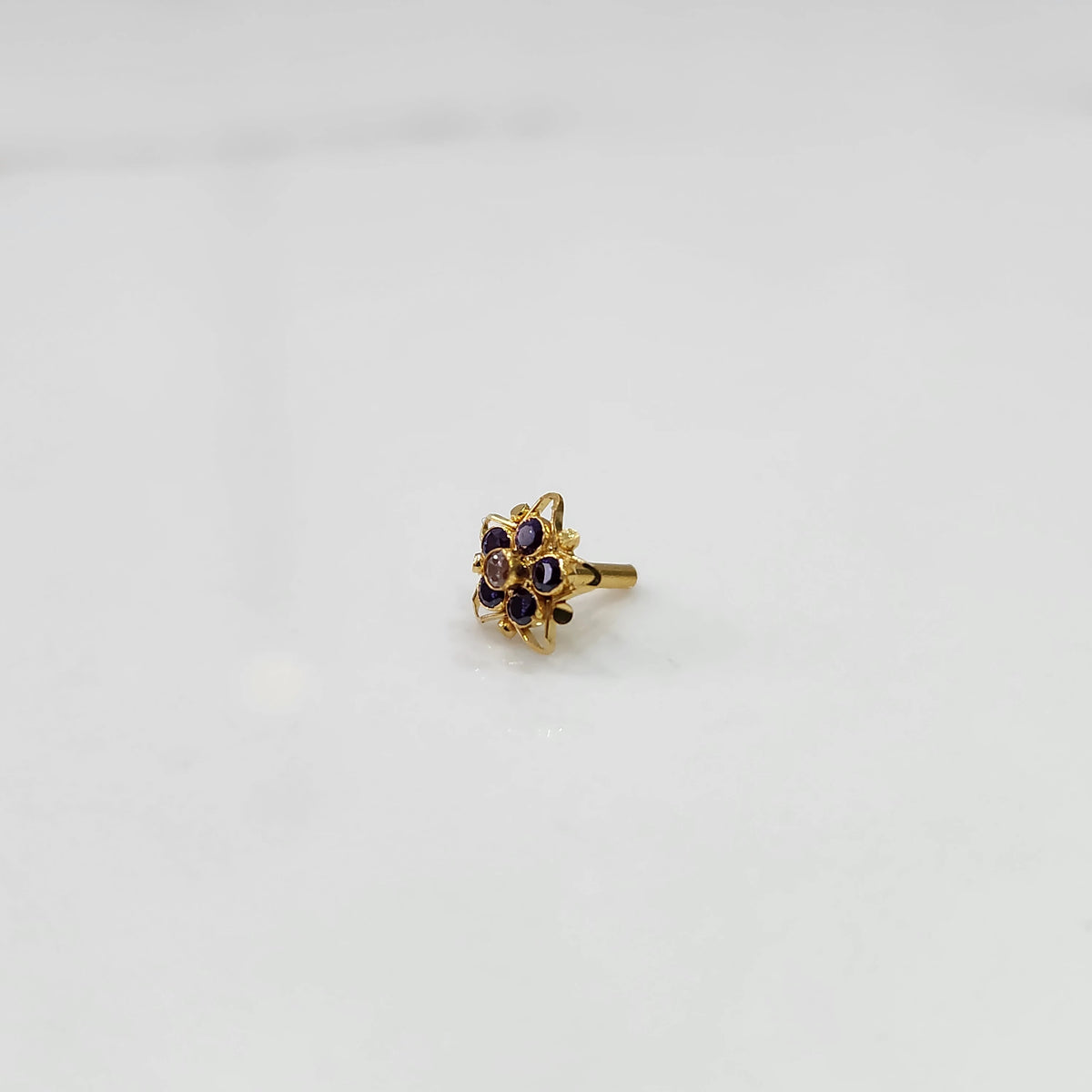 Gold nose pin featuring six-point star design with purple and champagne stone cluster