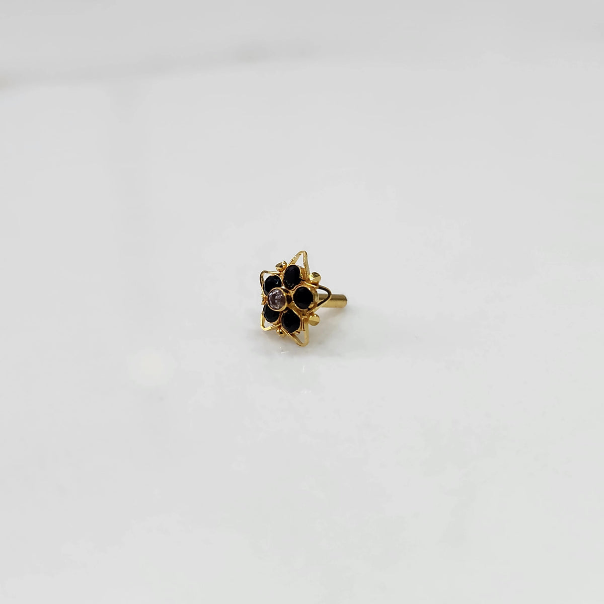Side view nose pin design gold with black stone floral pattern on white background