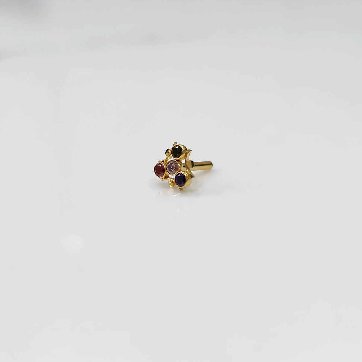 Traditional gold nose stud with black, red, pink, and purple stones in freeform setting